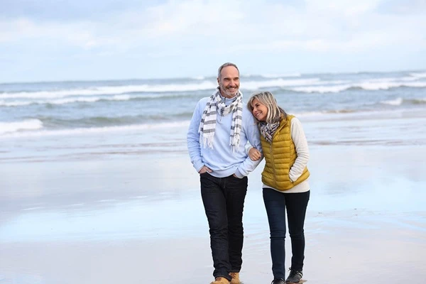 A couple strolling along the sandy beach, enjoying a peaceful walk by the ocean's edge.