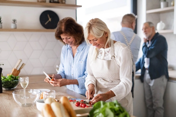 Two women in a kitchen chopping vegetables and preparing food for a meal together